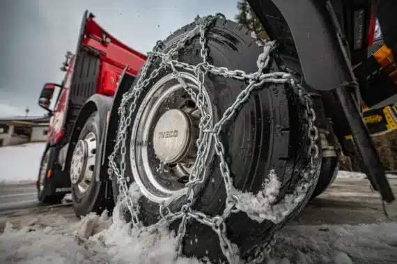 Detailný pohľad na záberové reťaze Pewag namontované na pneumatike nákladného vozidla.