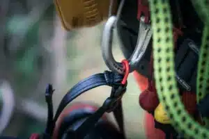 Pútko na podbradnom pásiku pilčíckej prilby Husqvarna Spire Vent uchytené o karabínu.