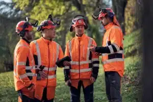 Tím lesných pracovníkov s pilčíckymi prilbami Husqvarna a chráničmi sluchu.