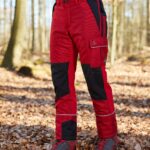 Predný pohľad na protiporezové nohavice Profiforest Extreme v červeno-čiernej farbe v lese.
