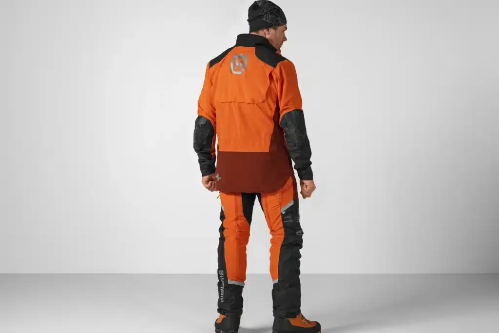 Zadný pohľad na pilčíka v bunde Husqvarna Technical Extreme, ktorý ukazuje predĺžený zadný diel a reflexné logo.