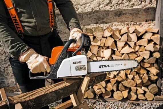 Používateľ v rukaviciach reže palivové drevo s motorovou pílou STIHL MS 170.
