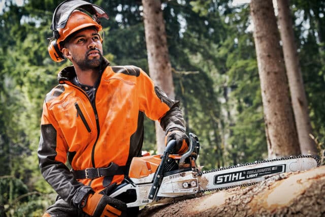 Profesionálny drevorubač drží ľahkú motorovú pílu STIHL MS 462 C-M VW v lese.