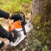 Drevorubač štartuje motorovú pílu STIHL MS 400 C-M v lese.