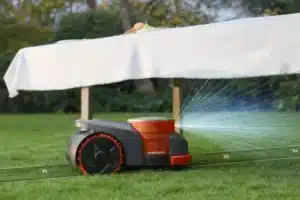 Kosačka Segway Navimow podchádza pod záhradný stôl.
