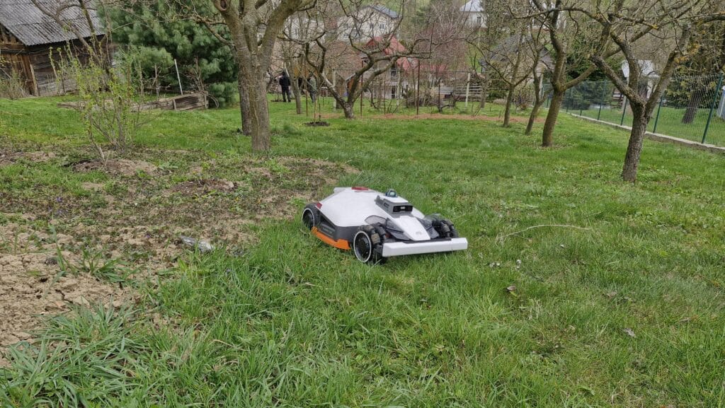 Robotická kosačka Luba 3 na záhrade plnej stromov a zložiteho terénu.