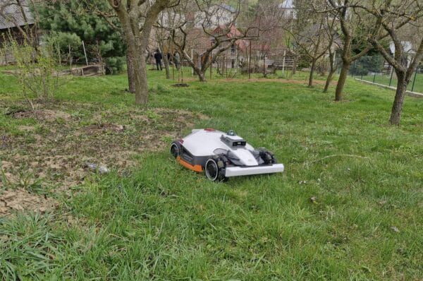 Robotická kosačka Luba 3 na záhrade plnej stromov a zložiteho terénu.